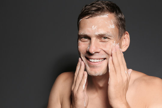 Man Washing Face With Soap On Dark Background