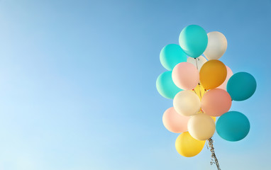Bunch of colorful balloons against clear blue sky. Space for text