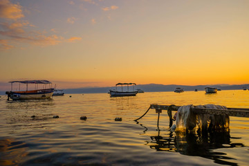 Sunrise in lake Ohrid with boats peacefully floating on the water  in late summer