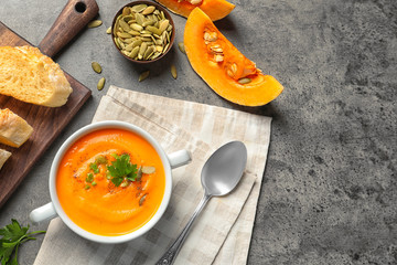 Flat lay composition with bowl of pumpkin soup on table. Space for text