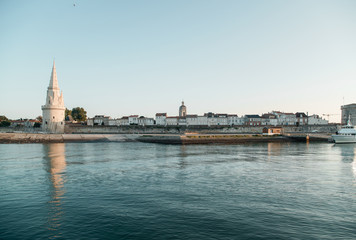 Fototapeta na wymiar La Rochelle, France: 26 August 2018: Embankment at the La Rochelle city on the coast of Atlantic ocean with medieval fortification towers. Early morning, sunrise