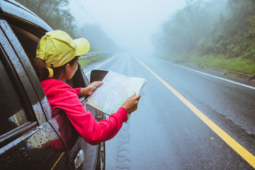 Asian women travel relax in the holiday. Traveling by car park. View map for Nature tours during...