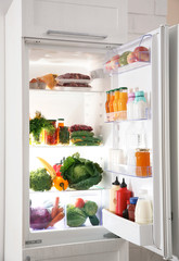 Modern refrigerator full of products in kitchen