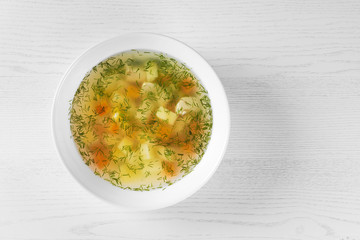 Bowl of fresh homemade soup to cure flu on wooden background, top view with space for text