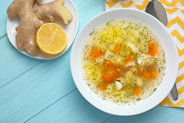 Flat lay composition with bowl of fresh homemade soup to cure flu on wooden background