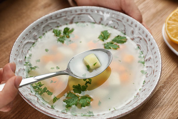 Sick woman eating fresh homemade soup to cure flu at table, closeup