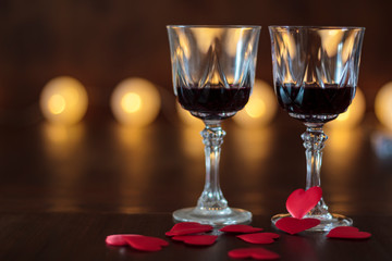 Two glasses of red wine and hearts on a wooden table