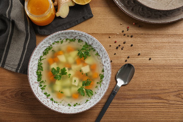 Flat lay composition with bowl of fresh homemade soup to cure flu on wooden background