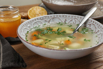 Bowl of fresh homemade soup to cure flu on wooden table