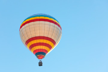 Fototapeta na wymiar Colorful hot air balloon flying in blue sky. Space for text