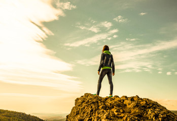 the figure of a girl on top of a mountain against a cloudy sky. sports, outdoor activities, travel,...