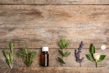 Essential oil and ingredients on wooden background, flat lay. Space for text