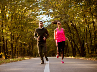 Athletic couple running together on the forest trail