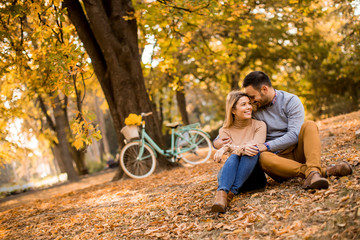 Young couple sitting on ground in autumn park - Powered by Adobe