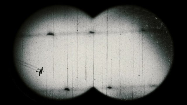 World War II era military airplanes and barbed wire fence. Retro style. View through binoculars