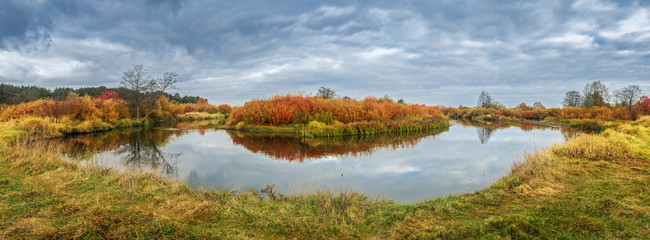 Autumn panoramic landscape with river in colorful meadow.