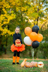 Girl holding pumpkin at Halloween party with orange and black balloons