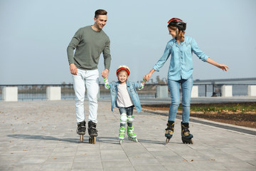Happy family roller skating on embankment. Active leisure