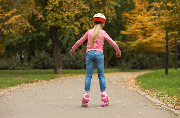 Cute girl roller skating in autumn park