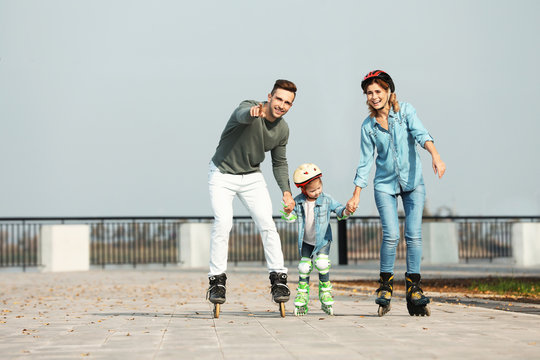 Happy Family Roller Skating On Embankment. Active Leisure