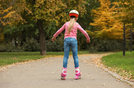 Cute girl roller skating in autumn park