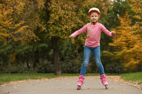 Cute girl roller skating in autumn park. Space for text