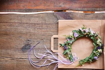 Handmade floral tiara made of flowers lie on wooden background. Fashionable hand made wreath of flowers head wear. Hand crafted fashion accessories