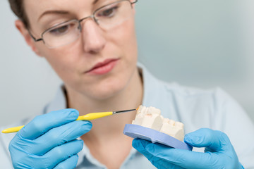 Zahntechnikerin färbt einen Zahnersatz im Zahnlabor