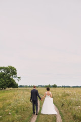 Young wedding couple walking on field. Retro style