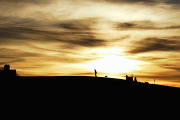 Fototapeta premium The walk. Silhouettes of an old man and his dog against dramatic sunset