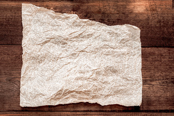 Sheet of parchment on a wooden background. Crumpled sheet of parchment paper as background, texture.