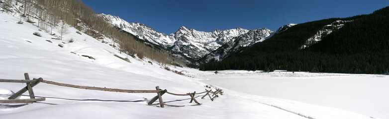 Beautiful snow covered Rocky Mountain peaks, split rail fence, near Vail Colorado