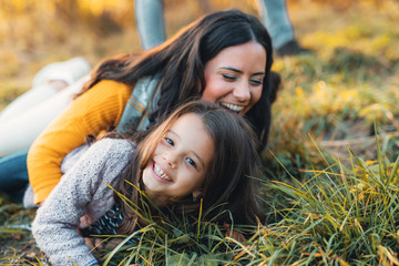 A portrait of young mother with a small daughter in autumn nature.