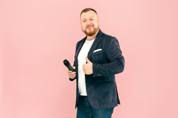 Young man with microphone on pink background, leading with microphone at studio concept. Human...