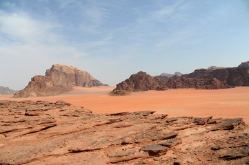 Fototapeta na wymiar Red mountains of the canyon of Wadi Rum desert in Jordan. Wadi Rum also known as The Valley of the Moon is a valley cut into the sandstone and granite rock in southern Jordan to the east of Aqaba