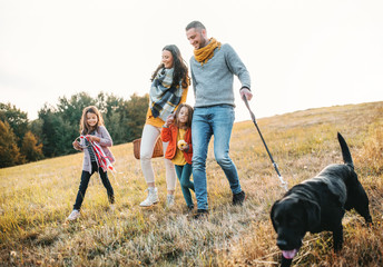 A young family with two small children and a dog on a walk in autumn nature.