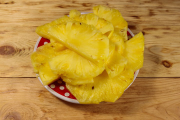 Pieces of pineapple in a plate on wooden table