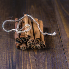 Cinnamon sticks tied with jute rope on old wooden background in rustic style. Winter Christmass holiday concept. Close up.