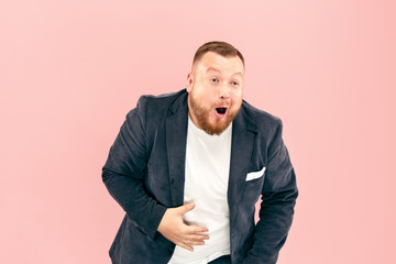 Young man with microphone on pink background, leading with microphone at studio concept. Human emotions and facial expressions concepts. Trendy colors
