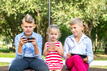 Fototapeta premium busy kids looking at their phones texting sms and playing sitting outside