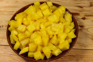 Diced pineapple in a plate on wooden table. Top view