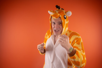 pajamas in the form of a giraffe. emotional portrait of a guy on an orange background. crazy and...