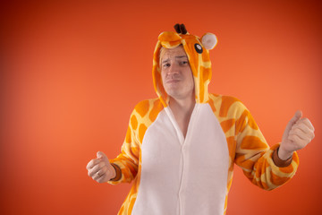 pajamas in the form of a giraffe. emotional portrait of a guy on an orange background. crazy and...