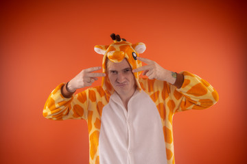 pajamas in the form of a giraffe. emotional portrait of a guy on an orange background. crazy and...