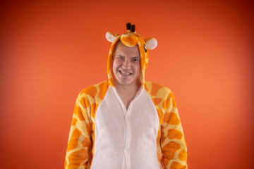 pajamas in the form of a giraffe. emotional portrait of a guy on an orange background. crazy and...