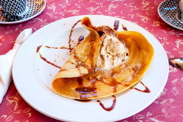 Crepe mit Haselnuss Eiscreme und Fruchsoße auf einem weißen Teller
