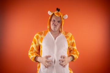 pajamas in the form of a giraffe. emotional portrait of a guy on an orange background. crazy and...