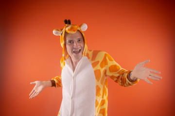 pajamas in the form of a giraffe. emotional portrait of a guy on an orange background. crazy and...