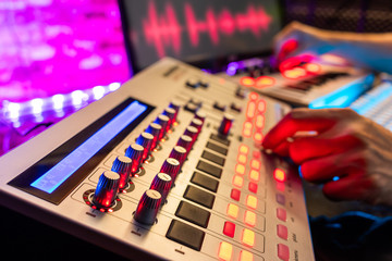 DJ, music producer hands editing on digital remixing controller equipment in sound studio, focus on...