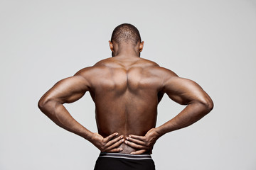 Fototapeta na wymiar Young man with back pain isolated on gray studio